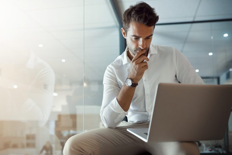 Business, businessman looking thoughtful while working on his laptop in the office