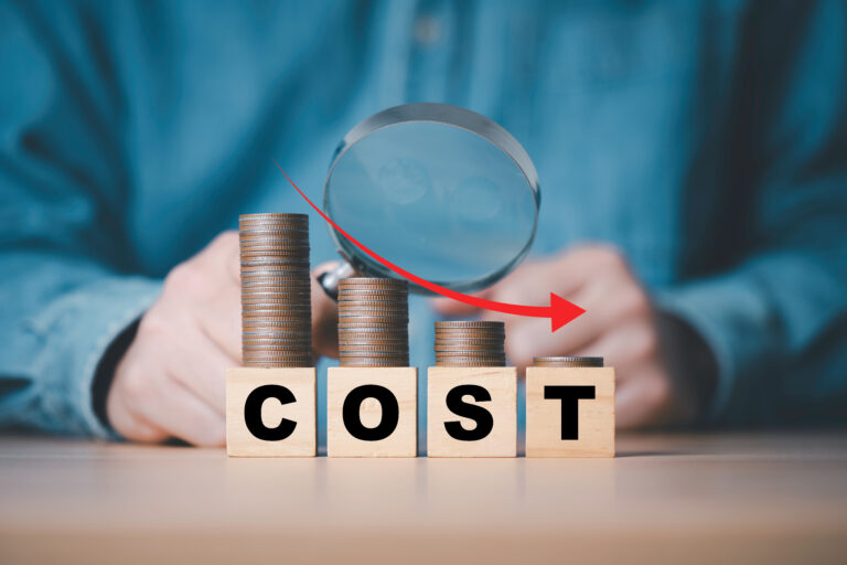 Businessman use magnifier glass and down arrow with decreasing of coins stacking for cost reduction in business cost saving to get more profit concept, Cut costs at your business