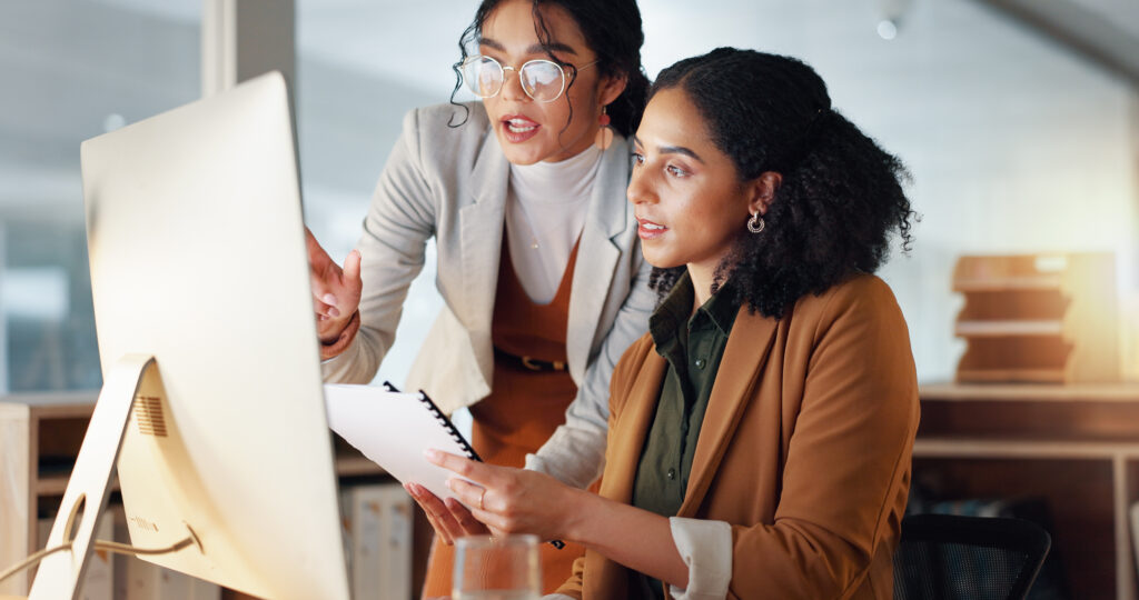 Communication, coaching and women in business with documents for training and project management on laptop. Instruction, mentor or leader talking to colleague in office, Cross train your staff