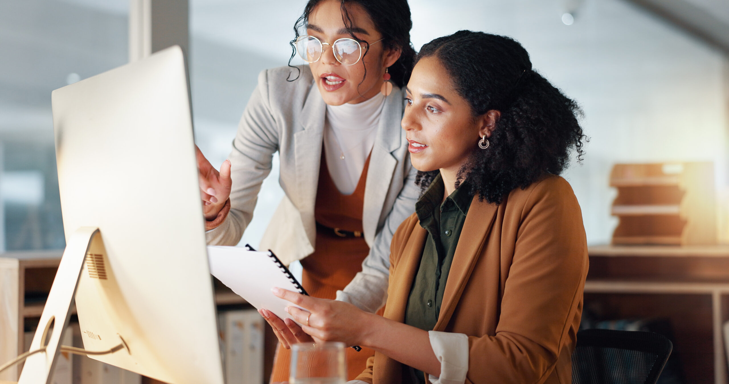 Communication, coaching and women in business with documents for training and project management on laptop. Instruction, mentor or leader talking to colleague in office, Cross train your staff