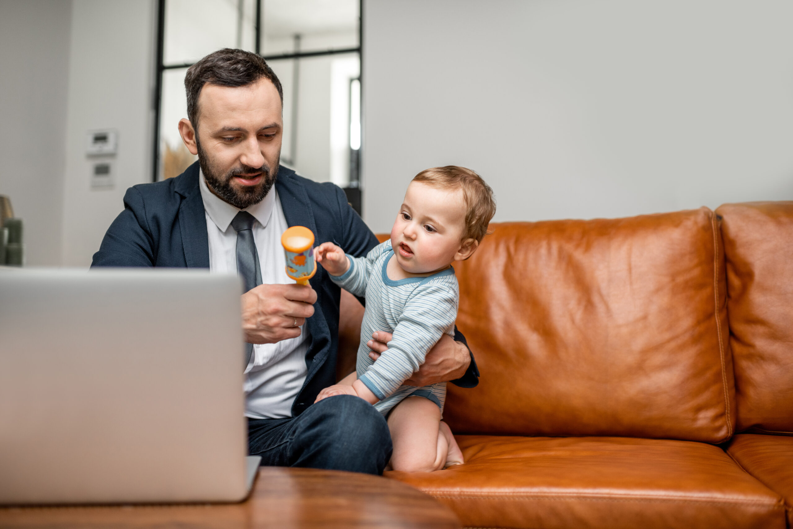Young businessman dad working on a laptop at home while taking care of his son. Lessons being a Dad has taught me about building a multi-million dollar business