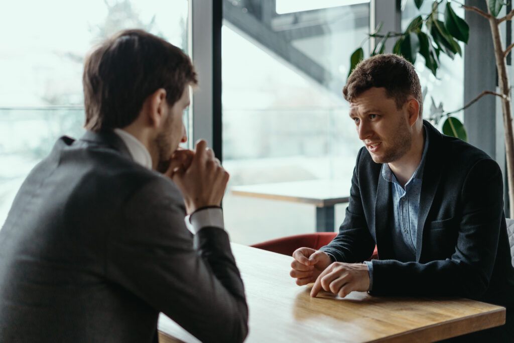 Focused businessman listening to business partner talking during discussion, thinking over his ideas while sitting at the table
