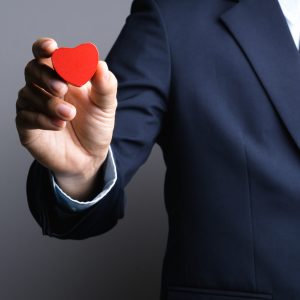Business man hand with wooden red heart object, Why being nice always pays off, kindness