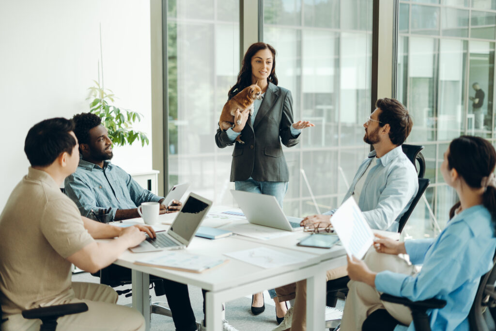 Businesswoman holding her pet dog while leading a diverse team meeting in a modern office, engaging in strategy discussions and collaborating on innovative projects. Business meeting concept, effective leadership