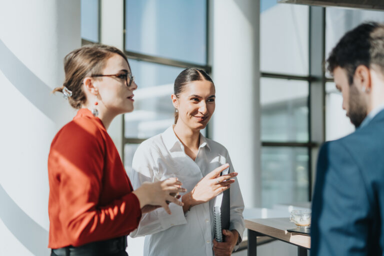 A group of business colleagues in a modern office setting engage in a relaxed conversation during a coffee break, fostering teamwork and collaboration, empower your team