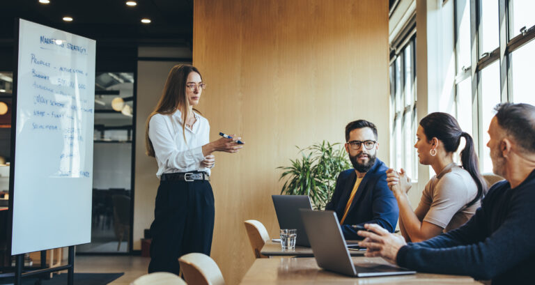 Businesswoman discussing her marketing strategy and ideas with her team, Female manager giving a presentation during a meeting with her colleagues in a modern workspace.