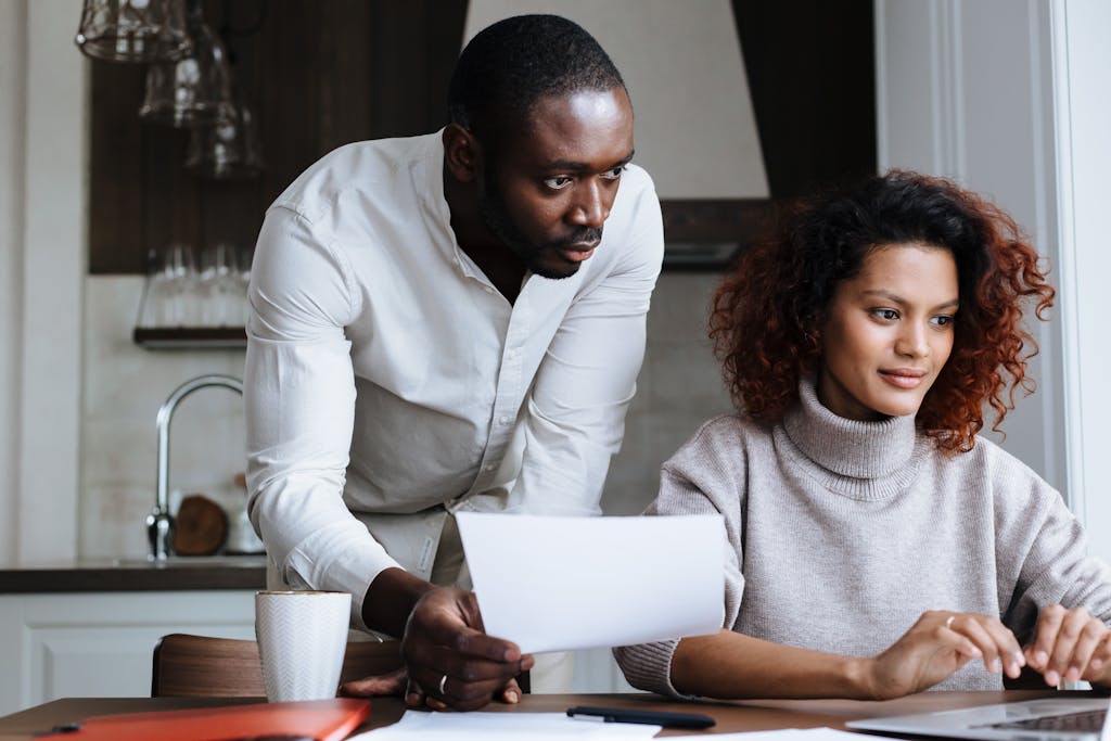 A diverse man and woman collaborating on a laptop in a stylish home kitchen.