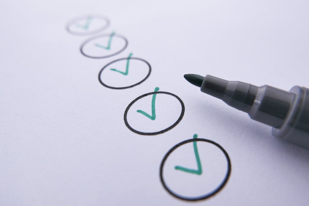 Close-up of a checklist with green checkmarks on white paper using a marker.