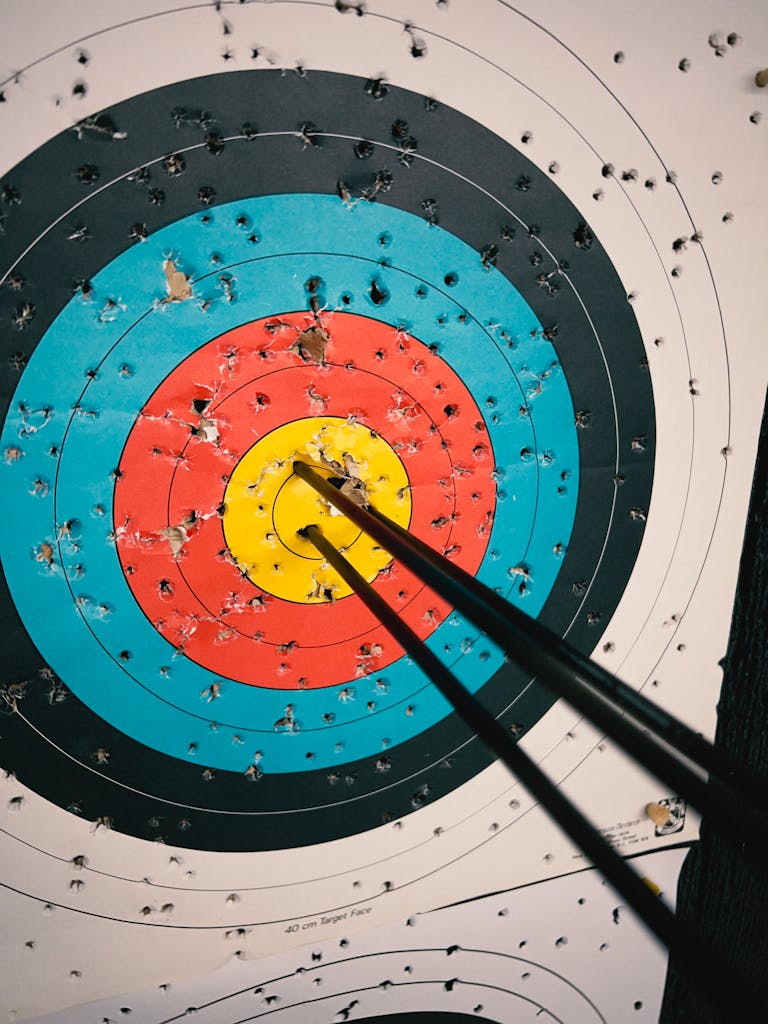 Close-up of an archery target with numerous bullseye hits and arrows lodged in the center.